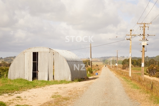 Typical New Zealand gravel road - Northland, North Island - Old corrugated iron farm shed in rural Northland near Whangarei                               