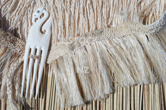 Closeup of a kahu pokowhiwhi  - Shoulder cloak made of white muka fibre and pokinikini and a heru made of bone - artist property release available
