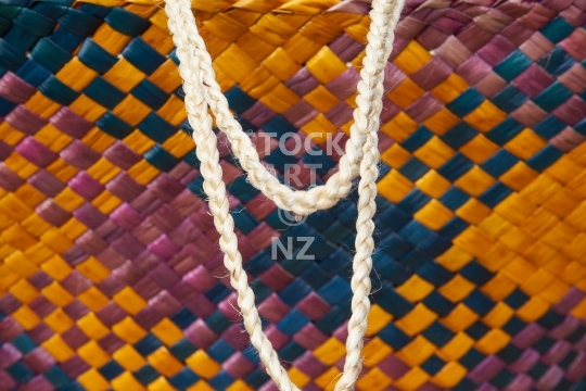 Closeup of a Maori kete - Flax weaving detail: bag handmade with takitahi weave in purple, blue and yellow colours, with a white muka fibre handle - photo comes with property release