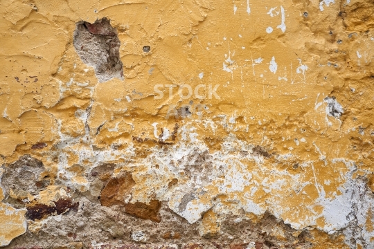 Closeup of an old crumbling ochre house wall full of texture