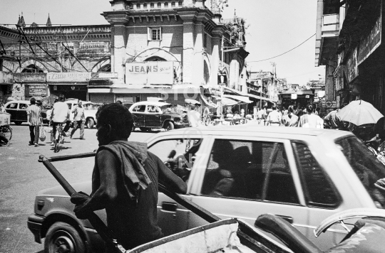Human rickshaw in Calcutta - Old traffic street scene with rickshaw wallah pulling a traditional wooden carriage in downtown Kolkata - vintage low resolution black & white photo from 1994