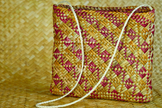 Kete whakairo with Papakirango pattern and white muka handles - New Zealand flax weaving fashion: handmade bag in red and orange (photo with artist release)