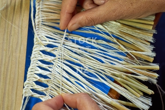 Unfinished flax weaving, weaver making a mini kahu from muka - Closeup with hands binding a knot