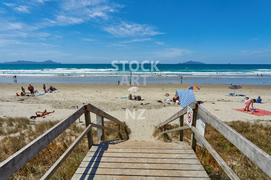 Waipu Cove beach in summer full of people - Bream Bay, Northland, NZ - Steps to the crowded and popular sandy beach with the Whangarei Heads and Hen & Chicken Islands in the background